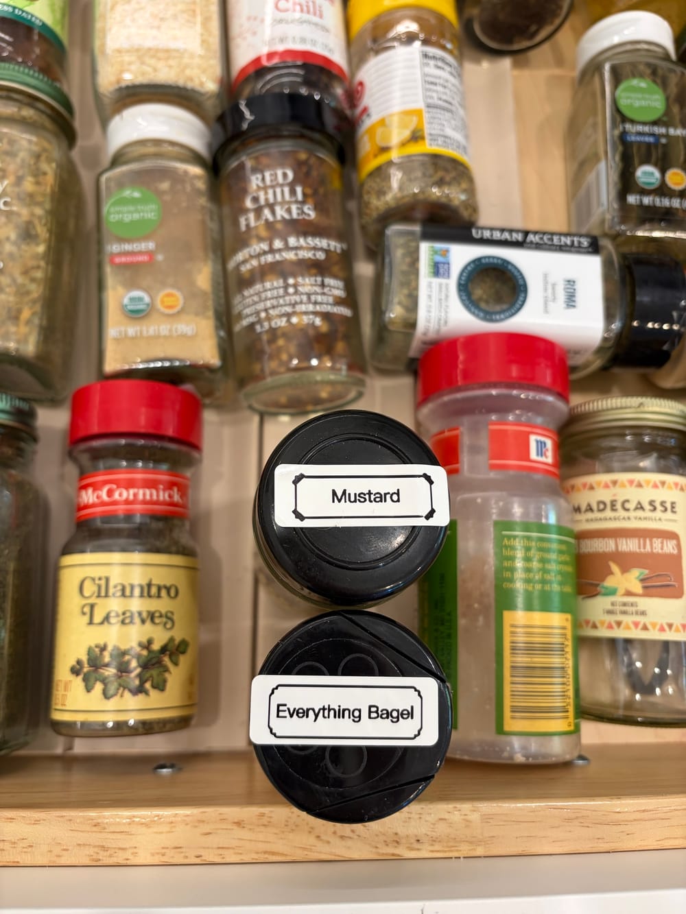 A spice drawer seen from above, with two black jar lids labeled Mustard and Everything Bagel